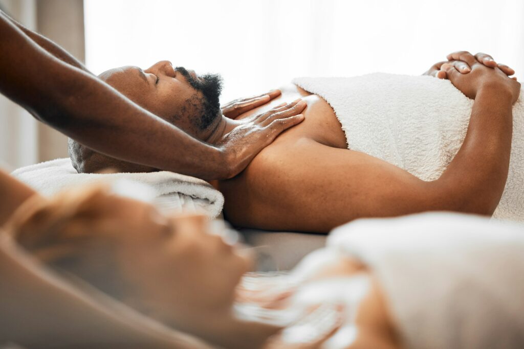 Black man, spa and couple massage for relax, skincare and wellness at resort on anniversary weekend